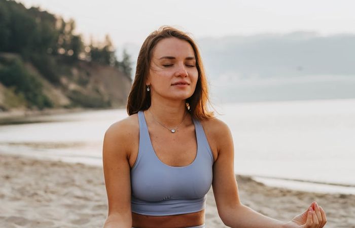 Person meditating in a calm natural environment at sunrise.